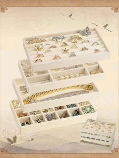 three white boxes filled with different types of jewelry