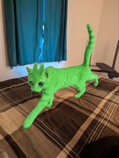 a green cat is jumping on a bed