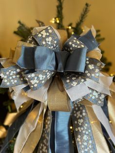 a blue and gold bow on top of a christmas tree