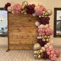 a large balloon arch in the middle of a room filled with pink, red and gold balloons