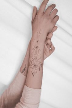 two hands holding each other with tattoos on them