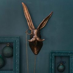 a metal bird head mounted to the side of a wall next to two framed pictures