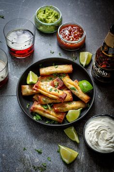 mexican food is served on a plate with sour cream sauces and lime wedges