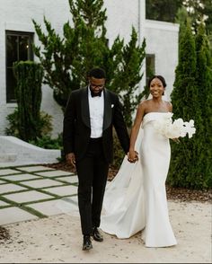 a bride and groom holding hands in front of a white house