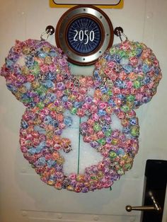 a mickey mouse clock hanging from the side of a door with flowers on it's face