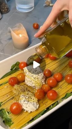 someone is pouring olive oil on some pasta with tomatoes and mozzarella cheeses