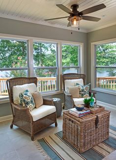 a living room with two wicker chairs and a coffee table in front of large windows