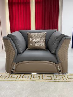 a gray and brown couch sitting on top of a white floor next to a red curtain