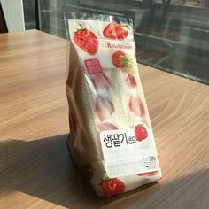 a bag of strawberries sitting on top of a wooden table