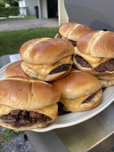 four cheeseburgers are stacked on top of each other in front of a house