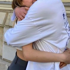 two people hugging each other outside on the street