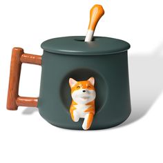 an orange and white cat sitting in a green pot with a wooden spoon sticking out of it