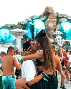 two people are hugging each other in front of a fountain with blue and white decorations