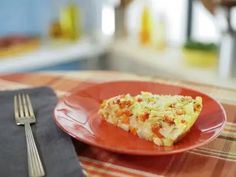 a red plate topped with a slice of pizza on top of a table next to a fork