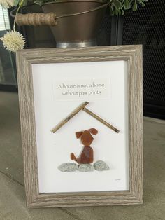 there is a picture frame with a dog holding a stick and a sign that says, a house is not a home without paw prints