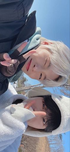 two young men standing next to each other in front of a blue and white sky