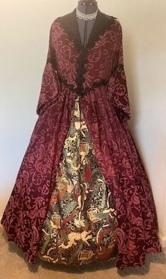 This high-quality, beautiful, historically accurate 16th century, court style gown with kirtle, will have you ready for a royal affair!   This is a beautiful 2-piece ensemble fits sizes 8-12.  The historically accurate 2-piece Tudor gown is made of maroon cotton, embellished with a design of acanthus leaves.  The bodice is fully lined with black satin and fastens easily in the front with hooks inside. The elegant sleeves split near the elbow and are accented by lined, open, pedal-cuffs.  The collar, waistline, elbows, and front are trimmed in black lace. The kirtle (apron-like underskirt) is made of cotton with a lush organic print of gold, green, black, and maroon.  Gown-approximately 59" shoulder to hem Kirtle- approximately 45" waist to hem, and ties in the back.  The gown is constructe Elegant Baroque Medieval Dress For Fancy Dress, Baroque Historical Design Gown For Costume Party, Victorian Medieval Dress Ball Gown For Fancy Dress, Victorian Medieval Ball Gown For Fancy Dress, Medieval Ball Gown Dress With Historical Design For Costume, Historical Ornate Medieval Dress For Fancy Dress, Elegant Medieval Dress For Fancy Dress, Baroque Gown With Historical Design For Costume, Baroque Medieval Dress For Fancy Dress