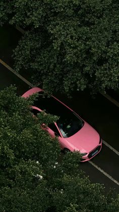 a pink car is parked in the middle of some trees