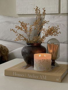 a candle sits on top of a book next to a vase with flowers and candles