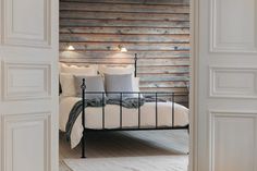 an open door leading to a bedroom with a white bed and brick wall behind it