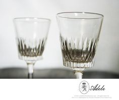 two clear wine glasses sitting on top of a table next to each other, one is empty