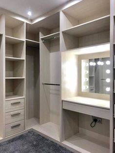 an empty walk - in closet with lights on the shelves and drawers, along with a rug