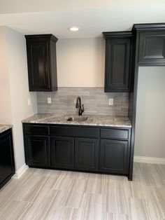 an empty kitchen with black cabinets and marble counter tops in the middle of the room