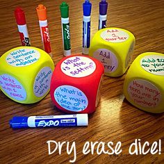 four dices with writing on them sitting on a wooden table next to markers and pens