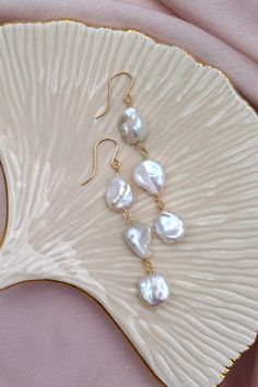 These elegant dangle earrings feature lustrous AA+ 10-12mm white keshi freshwater pearls, each uniquely shaped to showcase their natural beauty. The pearls are delicately linked with high-quality gold-filled wire, adding a touch of luxury and durability. The earrings are finished with simple yet sophisticated gold-filled ear hooks, making them a perfect accessory for any occasion. Keshi Pearl Earrings, Beads Craft Jewelry, Keshi Pearls, Ear Hook, Bead Crafts, Freshwater Pearls, Jewelry Crafts, Jewelry Earrings Dangle, Pearl Earrings