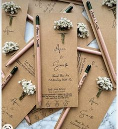 wedding stationery with pencils and flowers on them for guests to write their names