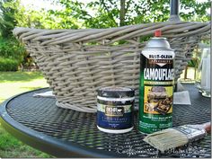 an outdoor table with some paint and a brush on it next to a wicker basket