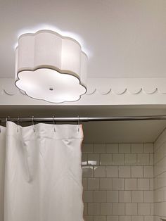 a bathroom with a white shower curtain and a light fixture above the bathtub area