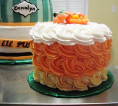 there is a large cake with orange and white frosting on the table next to it