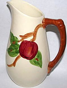 a white pitcher with an apple painted on it