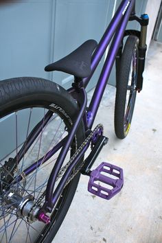 a purple bike parked in front of a garage door next to a bicycle chain guard