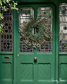 a green front door with a wreath on the top and two glass windows above it