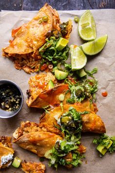 some food is laying out on a piece of paper with sauce and limes around it