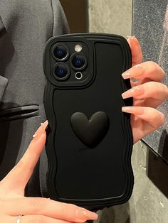 a woman holding up a black phone case with a heart on the front and sides