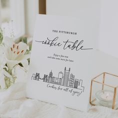 a table with a card and some flowers on it next to a small candle holder