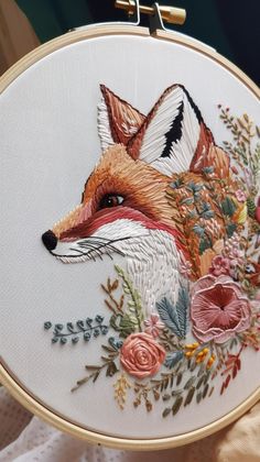 a close up of a embroidery on a piece of cloth with flowers and a fox