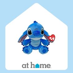 a blue stuffed animal sitting in front of the at home logo