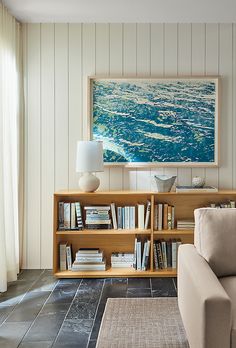 a living room with a couch, book shelf and painting on the wall behind it