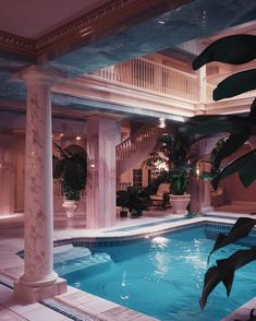 an indoor swimming pool surrounded by columns and plants