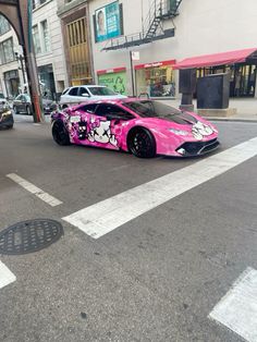 a pink sports car parked on the side of the road in front of a building