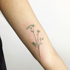 a woman's arm with a small tattoo of flowers on the back of her left arm