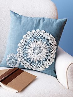 a blue pillow sitting on top of a white chair next to a book and pen