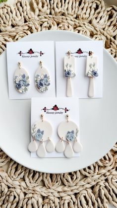 four pieces of white and blue flowered porcelain jewelry on a plate next to a woven place mat