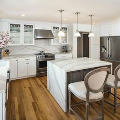 a large kitchen with white cabinets and marble counter tops, along with wooden flooring