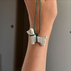 a woman's arm with a white dog charm on it and a green string