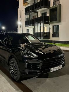 a black porsche cayen parked in front of a building